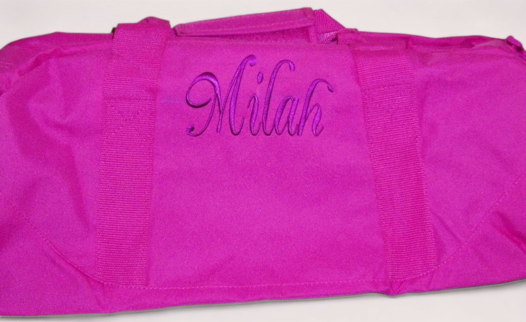 Pink duffle bag personalized with the name Milah in purple embroidery