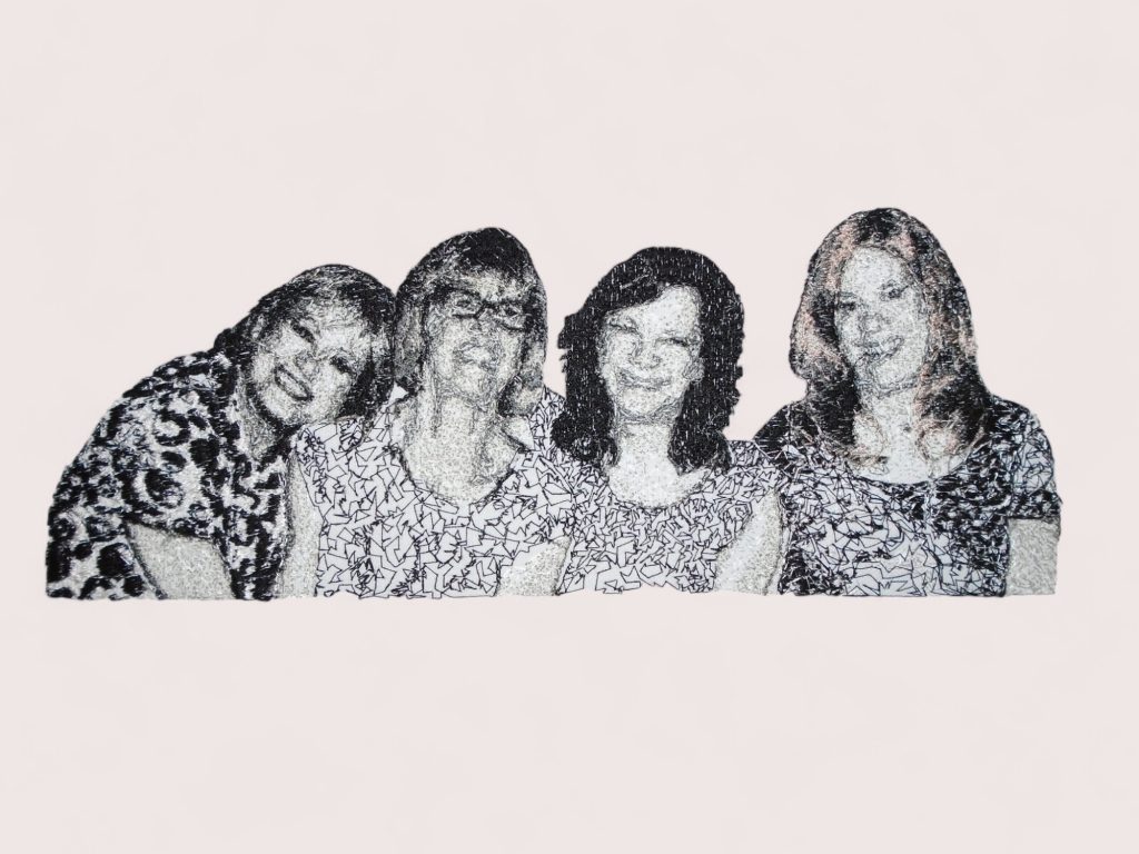 Black and white embroidered photo of four women in patterned shirts