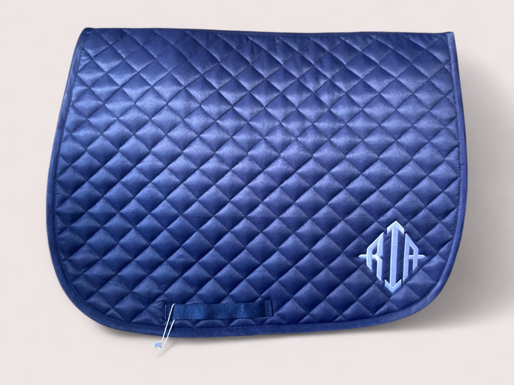 Blue quilted saddle pad with light blue RTA monogram embroidery