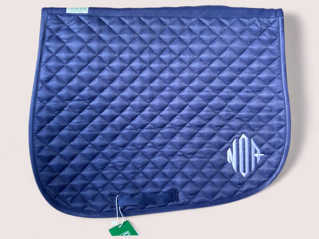 Saddle pad with stylized NOR embroidery in light blue